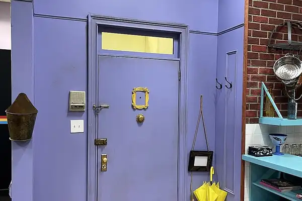 La porte d'entrée violette de l'appartement de Monica dans Friends, avec son cadre doré sur le judas.
